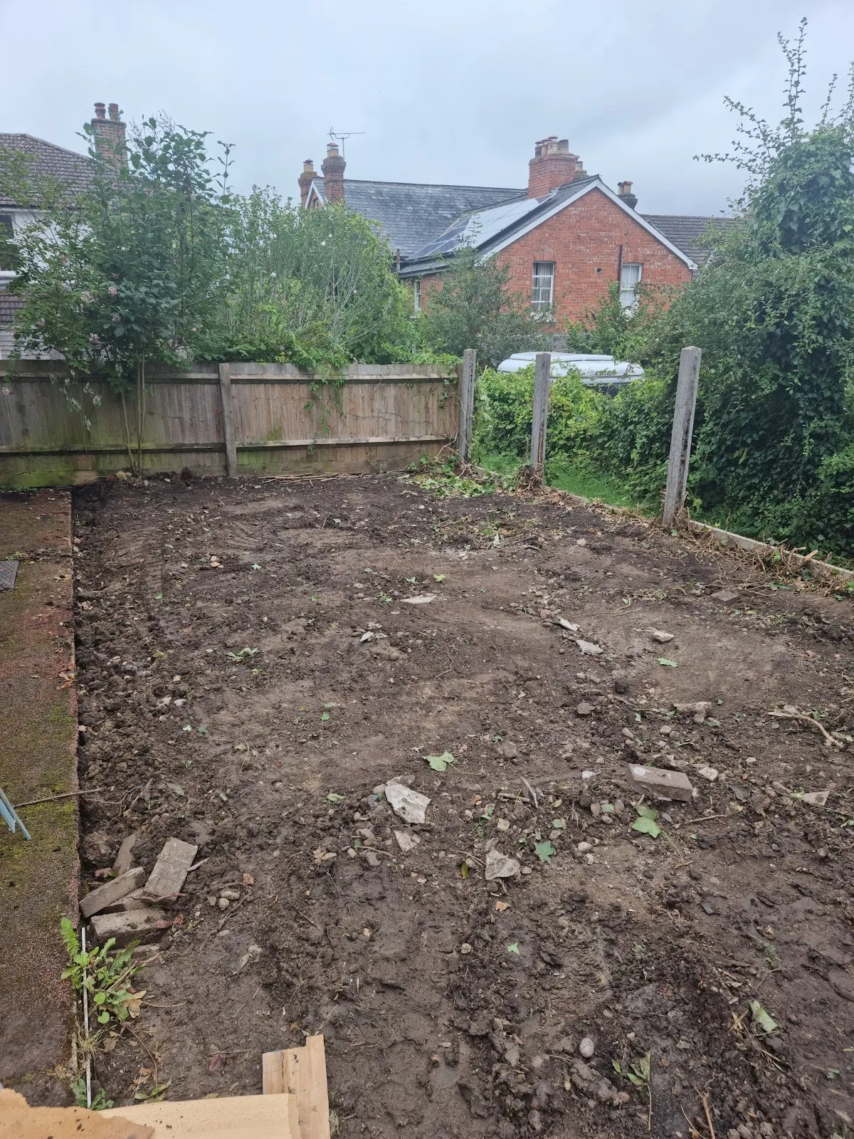 A rear garden taken back to bare soil, with the fence line behind