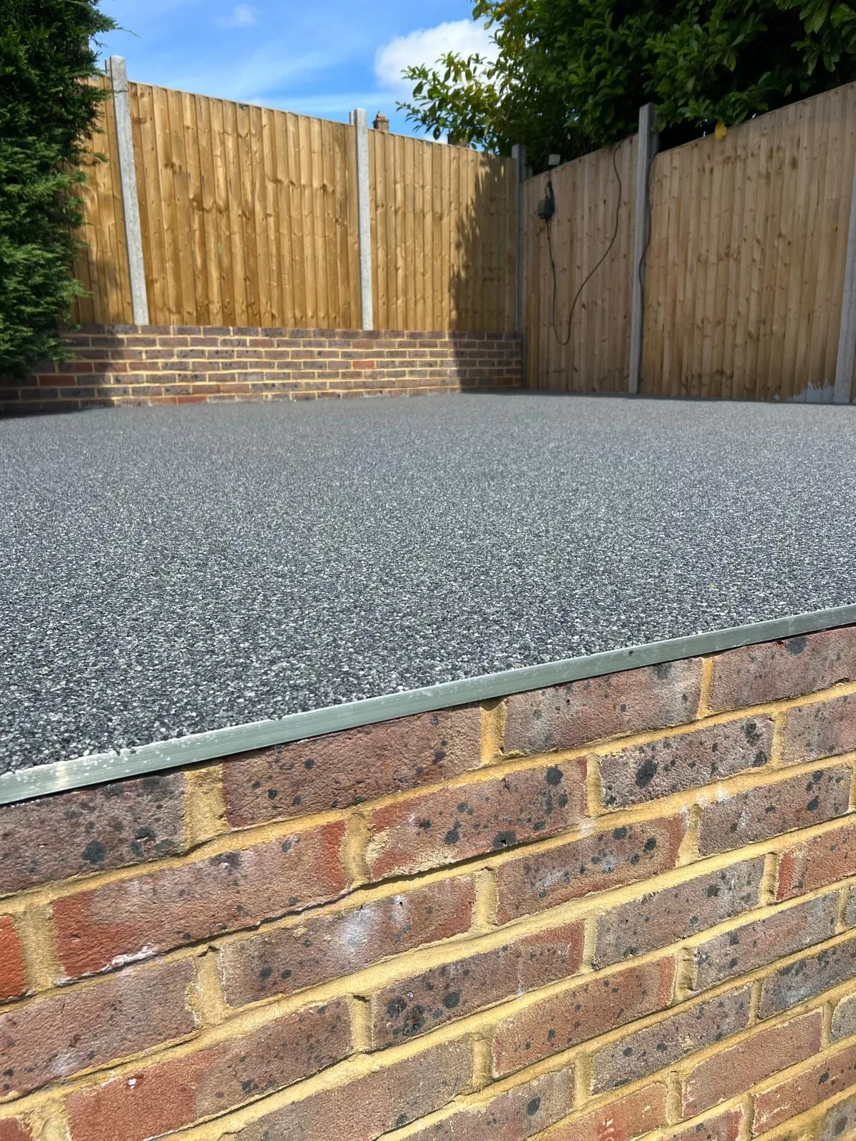 Resin patio area with brick edging and new fencing.