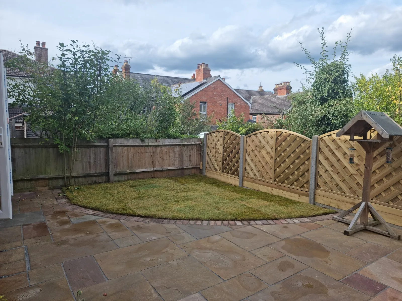 The finished sandstone patio with a curved lawn edge