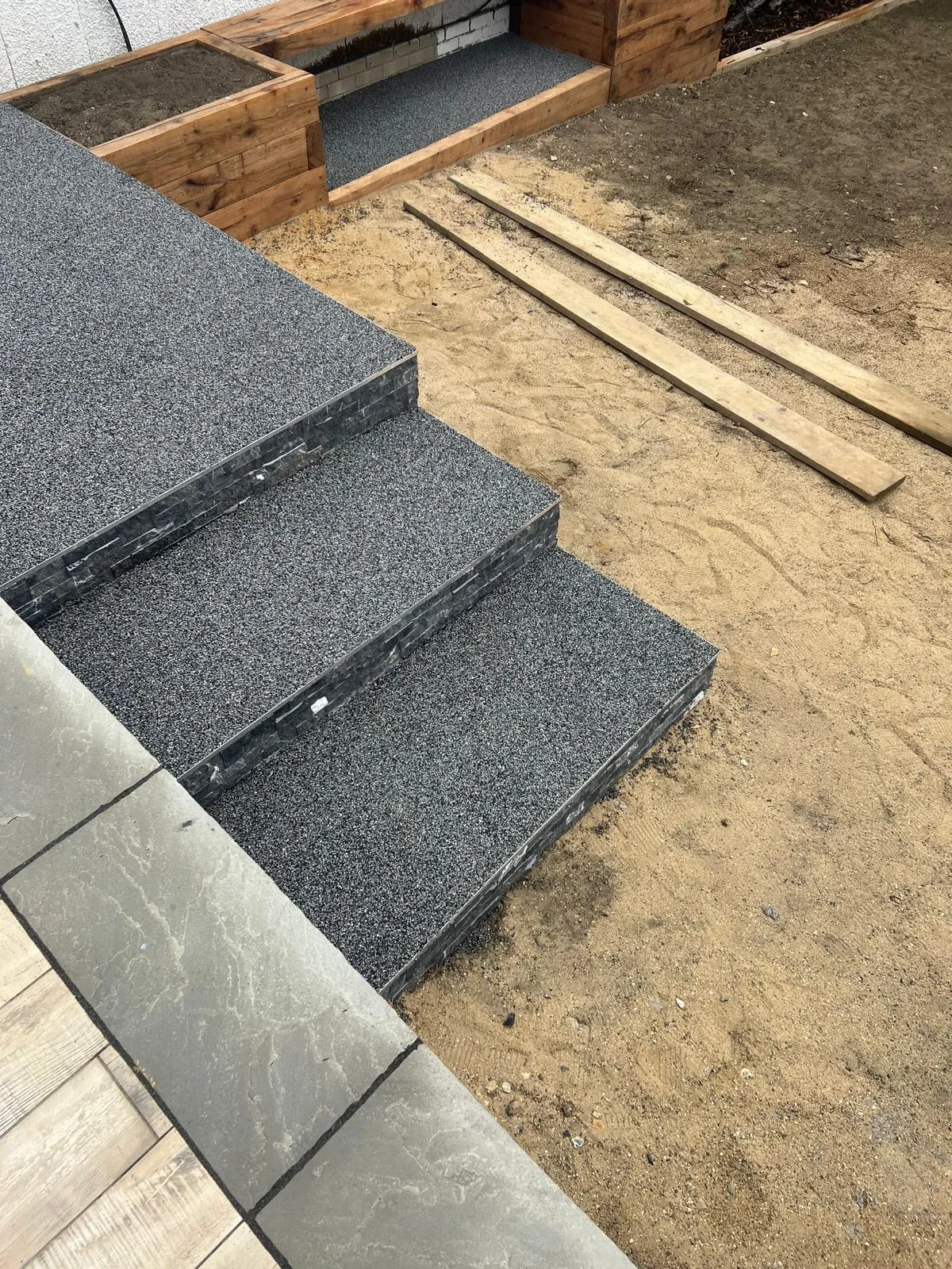 Granite steps being built, with the sand base still open around them.