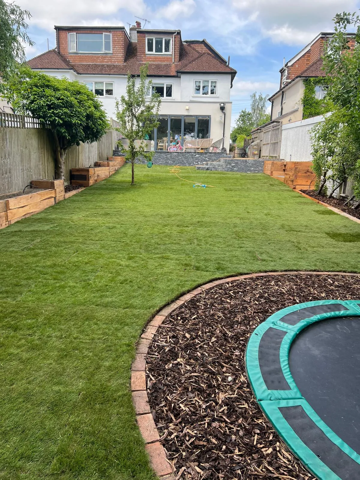 New turf and the trampoline sunk flush into brick edging.