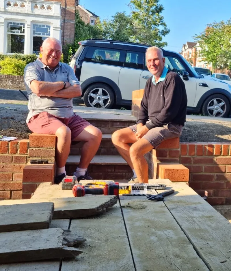 Doug, on the right, sitting on a new brick front wall